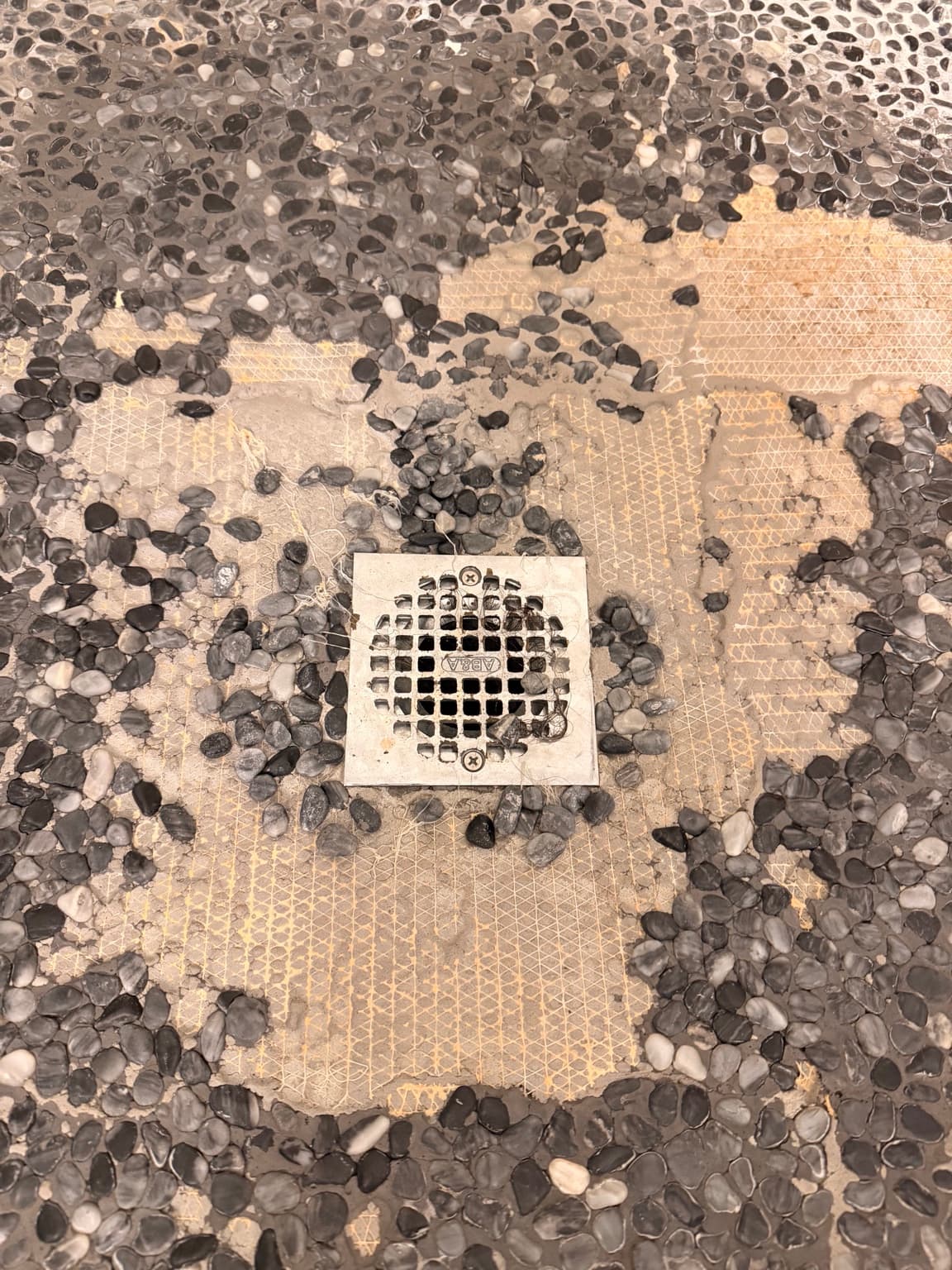 Shower floor pebble tile failure around drain