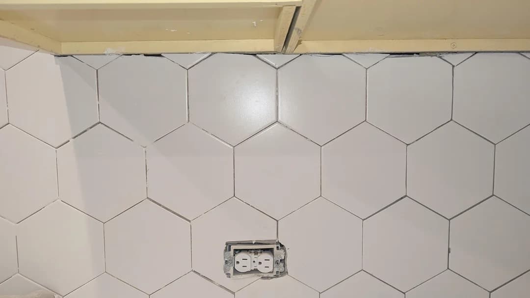 Hex tile backsplash with poorly planned outlet placement and cuts
